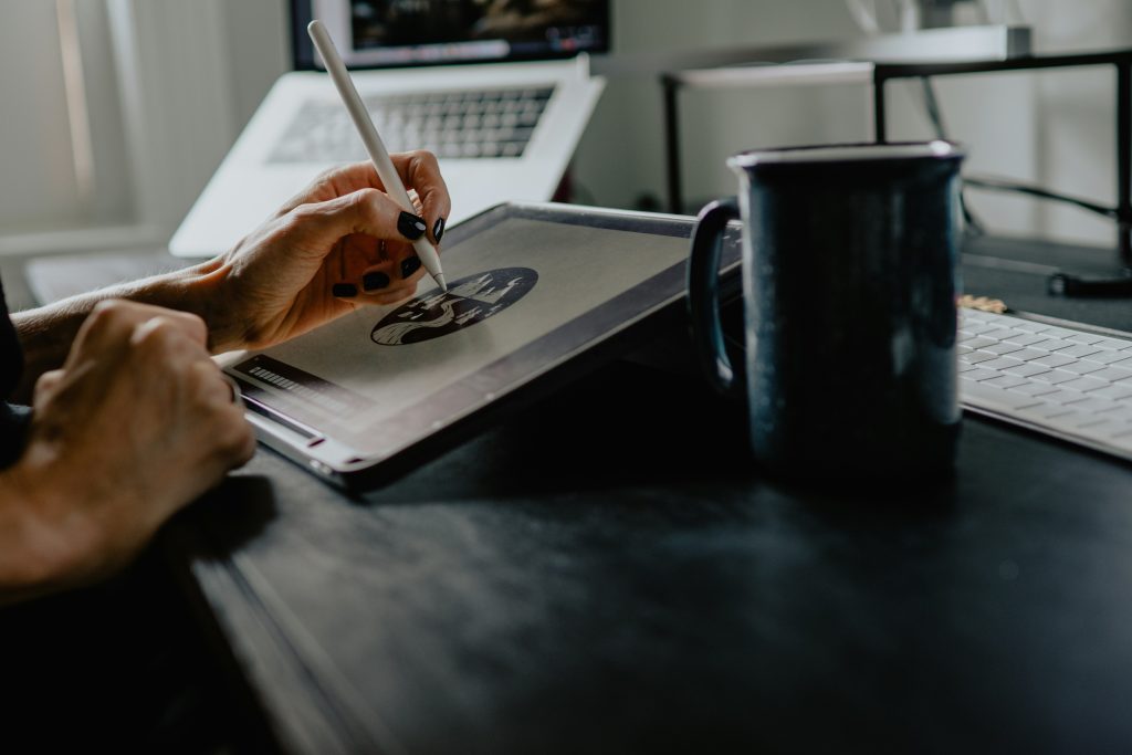 An entrepreneur using a stylus on a tablet to design a new business logo, representing the first steps in how to secure trademark priority in Ohio before selling.